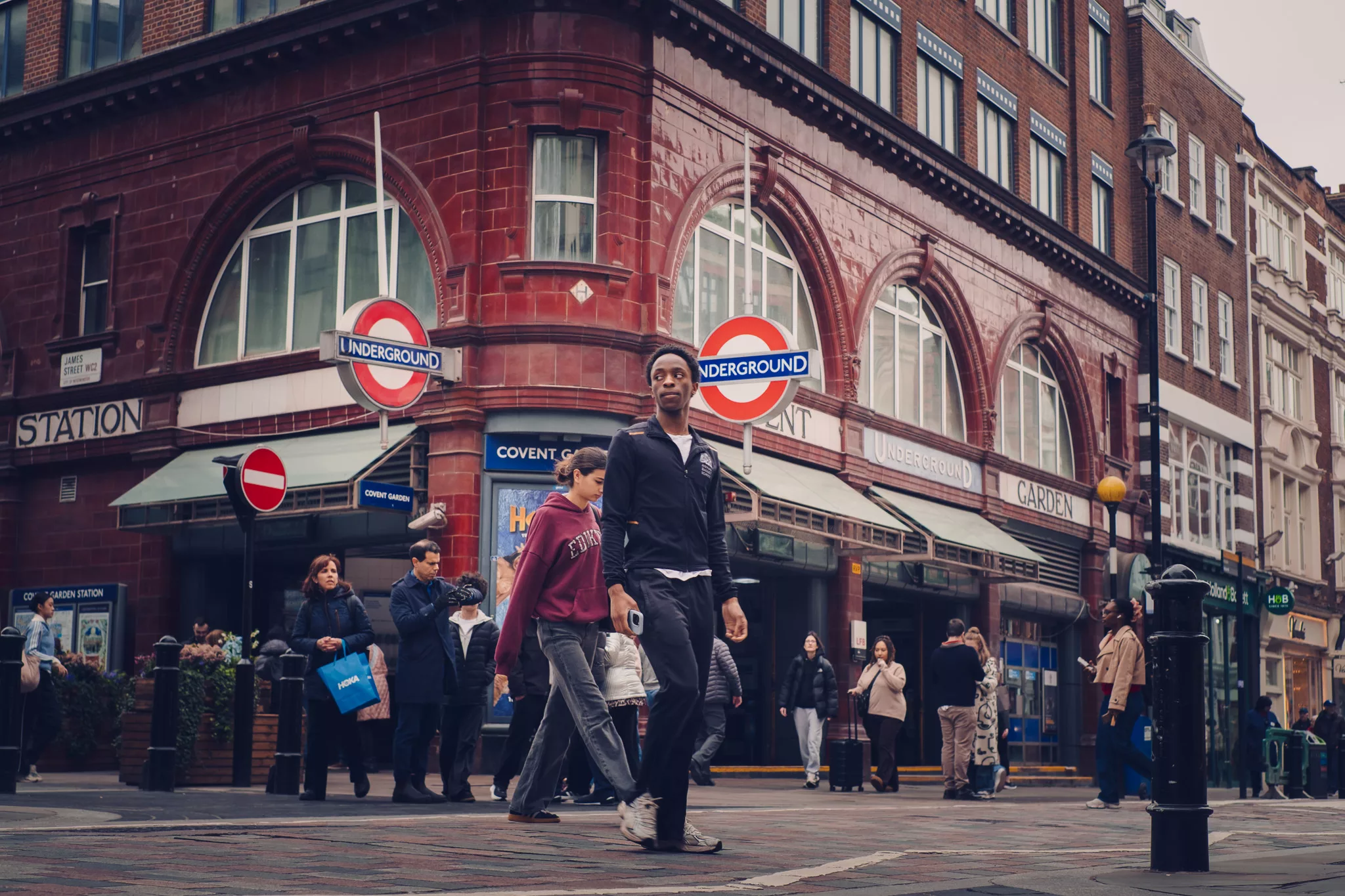 Young man crossing the street in front of Covent Garden tube station. Fujifilm X-T30 street photography challenge.